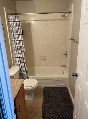 Compact bathroom with a bathtub, shower curtain, and sink.
