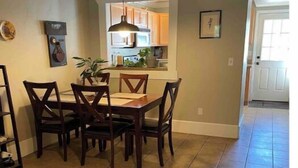A dining area with a wooden table and chairs, a hanging light fixture, and a kitchen in the background. - Clean, quiet, centrally located home (Salt Lake City)