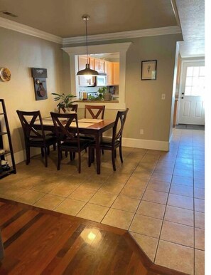 Enjoy meals in this stylish dining area with a wooden table and chairs, kitchen access, and framed artwork.