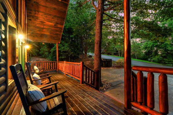 A wooden deck with chairs and a railing, overlooking a forested area. - Peaceful private, King Bed, hot tub, arcade, minutes to attractions and parkway (Sevierville)