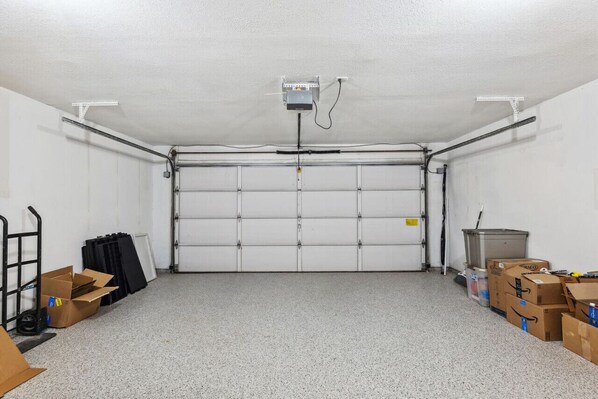 Eine Garage mit geschlossener Rolltür, einem an der Decke befestigten Projektor und verstreuten Kartons.