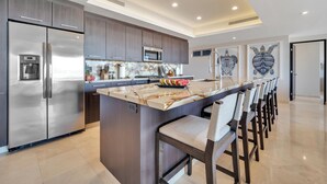 A modern kitchen with a large island, stainless steel appliances, and a seating area with bar stools. - Luxury Cabo Condo in Pedregal, 2 bedroom, 2 bath, City & Ocean Views (Cabo San Lucas)