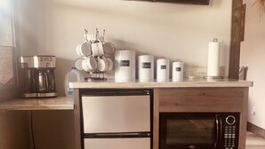 Eine kompakte Küche mit Kühlschrank, Mikrowelle, Kaffeemaschine und Aufbewahrungsbehältern.