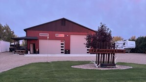 Ein rotes Bauernhaus mit überdachtem Bereich und einem weißen Wohnmobil davor.