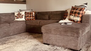 Ein Wohnzimmer mit Ecksofa, Couchtisch und einem gemusterten Teppich.