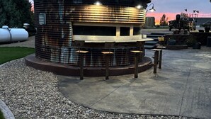 Ein rustikales, rundes Gebäude mit einer Metallbedachung und Holzbänken entlang des Außenrandes.