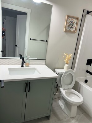 Une salle de bain avec un lavabo blanc, des toilettes et une baignoire.