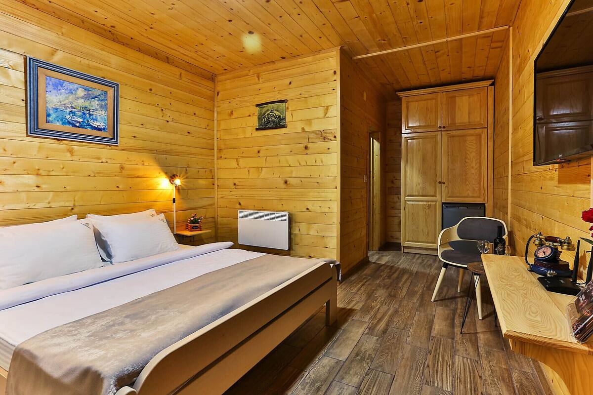 Una habitación de cabaña de madera con una cama, un escritorio, una silla y un radiador.