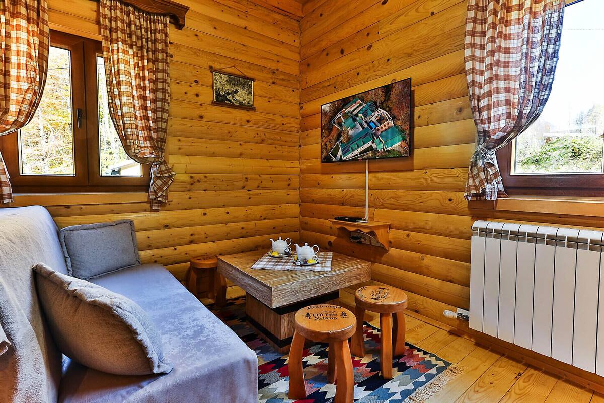 Una habitación de cabaña acogedora con sofá, una mesita con juego de té y un cuadro en la pared.
