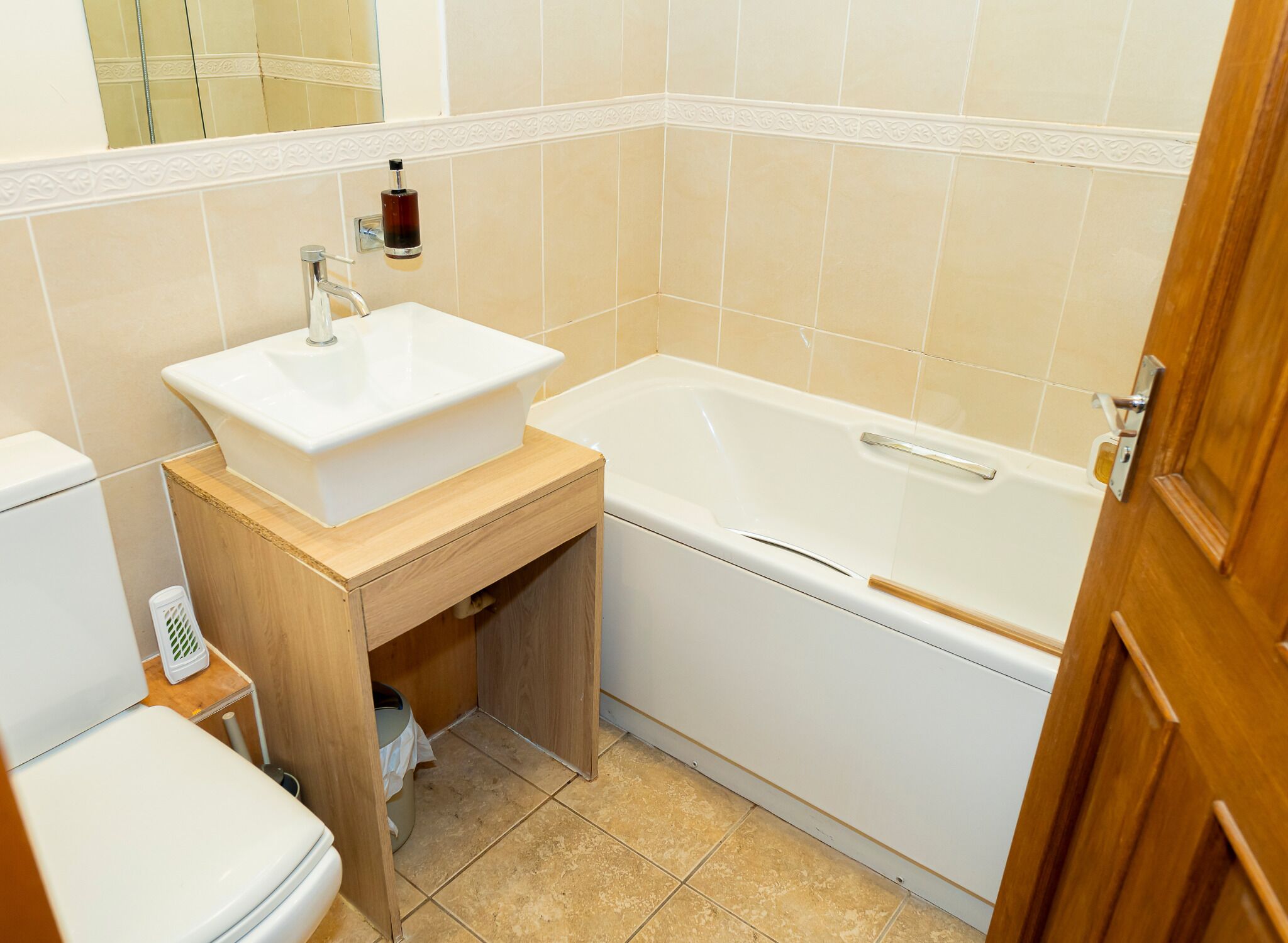 A bathroom with a white sink, a bathtub, and a wooden vanity.