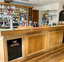 A bar area with multiple taps and shelves of bottles.