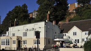 Le pub George, avec sa façade traditionnelle, ses tables à l’extérieur et un escalier menant à l’entrée.