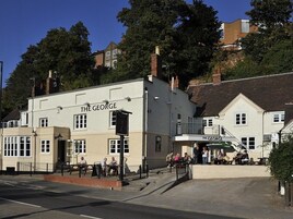 The George pub with a traditional facade, outdoor seating, and a staircase leading to the entrance.
