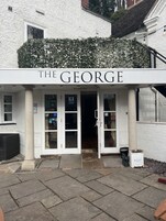 El exterior de The George, un edificio con fachada blanca, un letrero sobre la entrada y un pequeño porche.