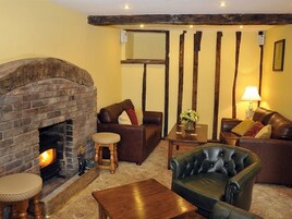 A cozy living room with a brick fireplace, leather sofas, and wooden furniture.