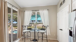 A small kitchen with a window, two chairs, a table, and a refrigerator. - The Minnion's Palace Villa (Kissimmee)