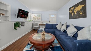 A modern living room with a blue sofa, a coffee table, and a TV mounted on the wall.