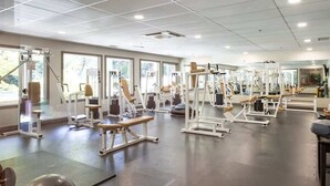 A gym with various exercise machines and benches. - Serenity on the Bay - Studio (Nanoose Bay)