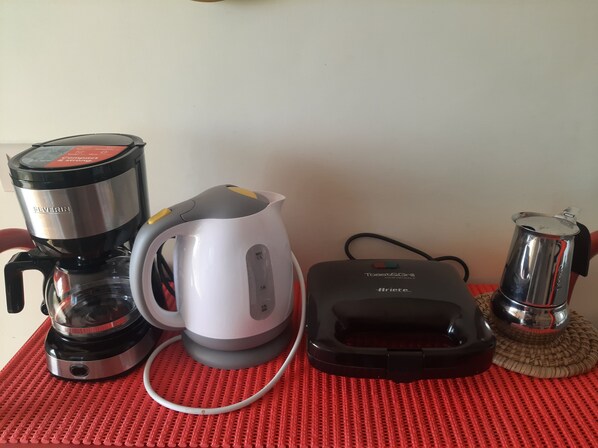 A coffee maker, a kettle, and a toaster on a red mat. - Leopin House open your eyes and fly beyond the sea (Sant'Alfio)