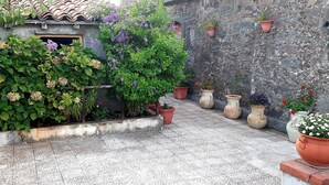 Un patio con plantas en macetas y un muro de piedra.