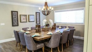 Une salle à manger avec une table en bois, des chaises à revêtement gris et un lustre.
