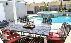 A patio with a table and chairs, a pool, and a wooden fence.