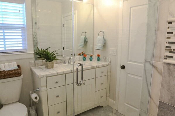 Une salle de bain comprenant des toilettes, un lavabo avec un miroir et un espace douche.