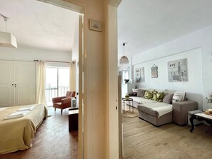 Una camera d'albergo con un letto, un divano, una sedia, un tavolino e una parete decorata con immagini di uno skyline urbano.