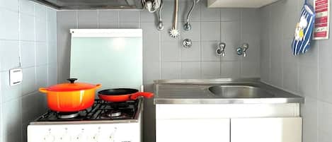 A compact kitchen with a stove, oven, and a sink.