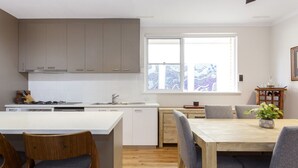 Una cocina moderna con una isla central, sillas de madera y una mesa de comedor.
