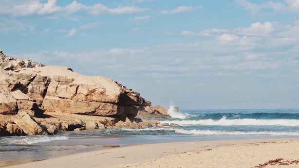 A beach with a rocky cliff and waves crashing onto the shore. - Lizandro´s  Pé  n' Areia (Mafra)