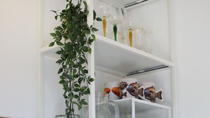 A kitchen counter with a hanging plant, a coffee maker, a jar, and a mug. - Lizandro´s  Pé  n' Areia (Mafra)