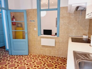 Una cucina con una porta blu, piastrelle a parete, un piano di lavoro bianco e un pavimento a motivi.