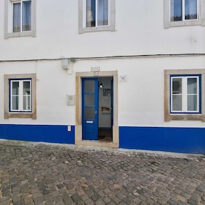 Ein Gebäude mit einer blauen Tür, einem Schild darüber und einem Kopfsteinpflaster.