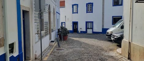 Eine gepflasterte Straße, gesäumt von Gebäuden, von denen einige mit blauen Akzenten versehen sind.