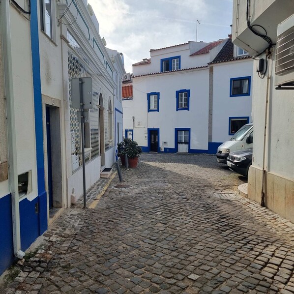 A cobblestone street with buildings on either side, some with blue trim.
