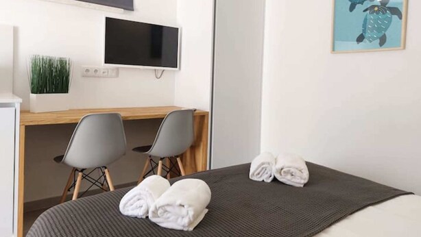 Une chambre d’hôtel comprenant un lit, deux chaises, un bureau, un téléviseur à écran plat et un tableau représentant des tortues.