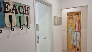 A hallway with a wall-mounted sign reading 'BEACH' and a door with a pop art painting. - Mocho's  - Apartment (Mafra)