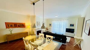 Ein Wohnzimmer mit einer Couch, einem Fernseher und einem Essbereich mit Stühlen und einem Tisch.