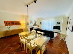 Un soggiorno con divano, televisore e zona pranzo con sedie e tavolo.