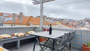 Eine Terrasse im Freien mit Tisch, Stühlen, einer Flasche und zwei Gläsern.