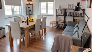 A cozy living room with a dining area, a bookshelf, and a sofa. - Ericeira - Parrot`s House (Mafra)