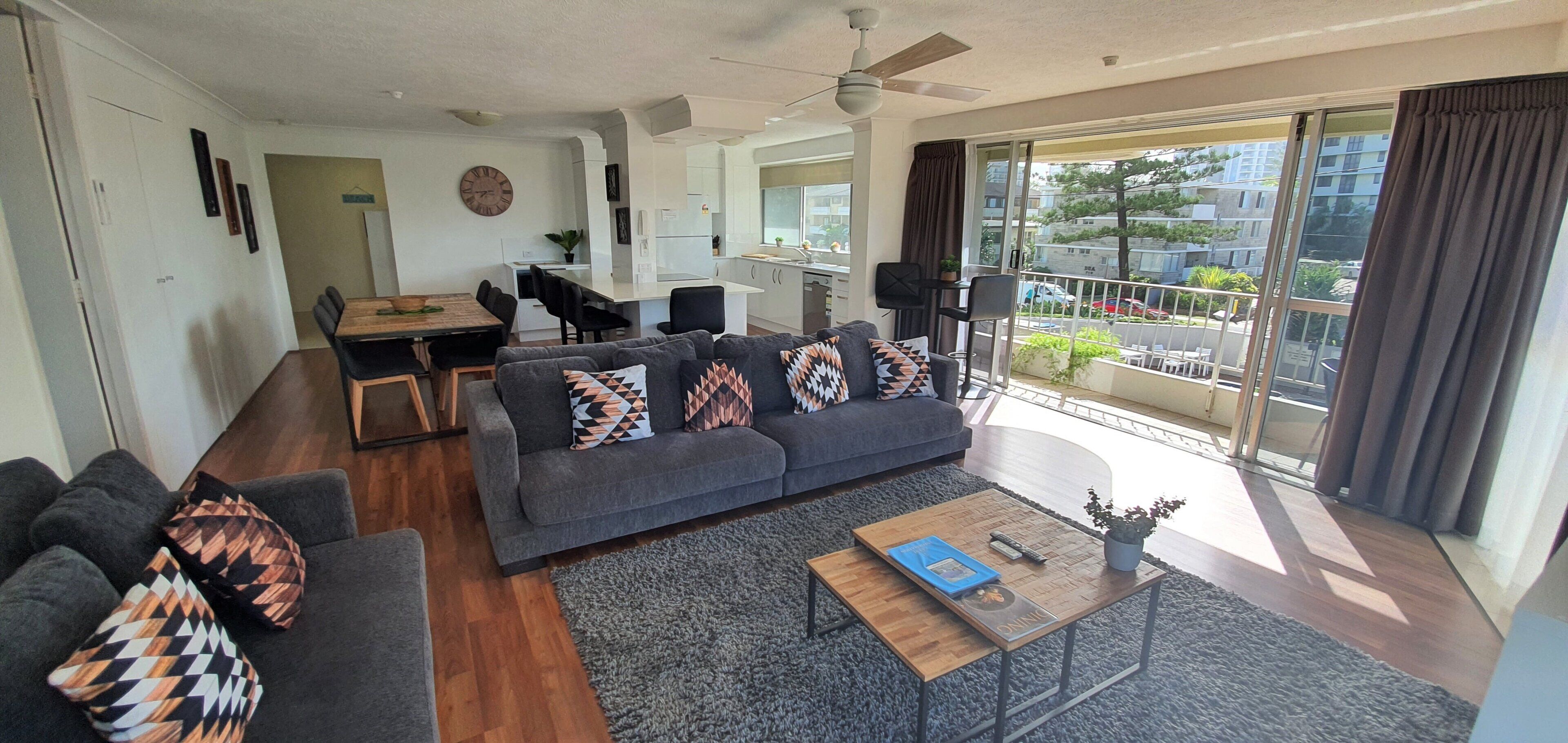 A modern living room with a sofa, coffee table, and dining area.