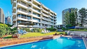 Ein modernes Hotel mit Schwimmbad, mehreren Balkonen und einem gepflegten Garten.