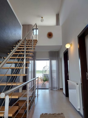 A modern interior with a wooden staircase, a view to the outside, and a radiator on the wall.