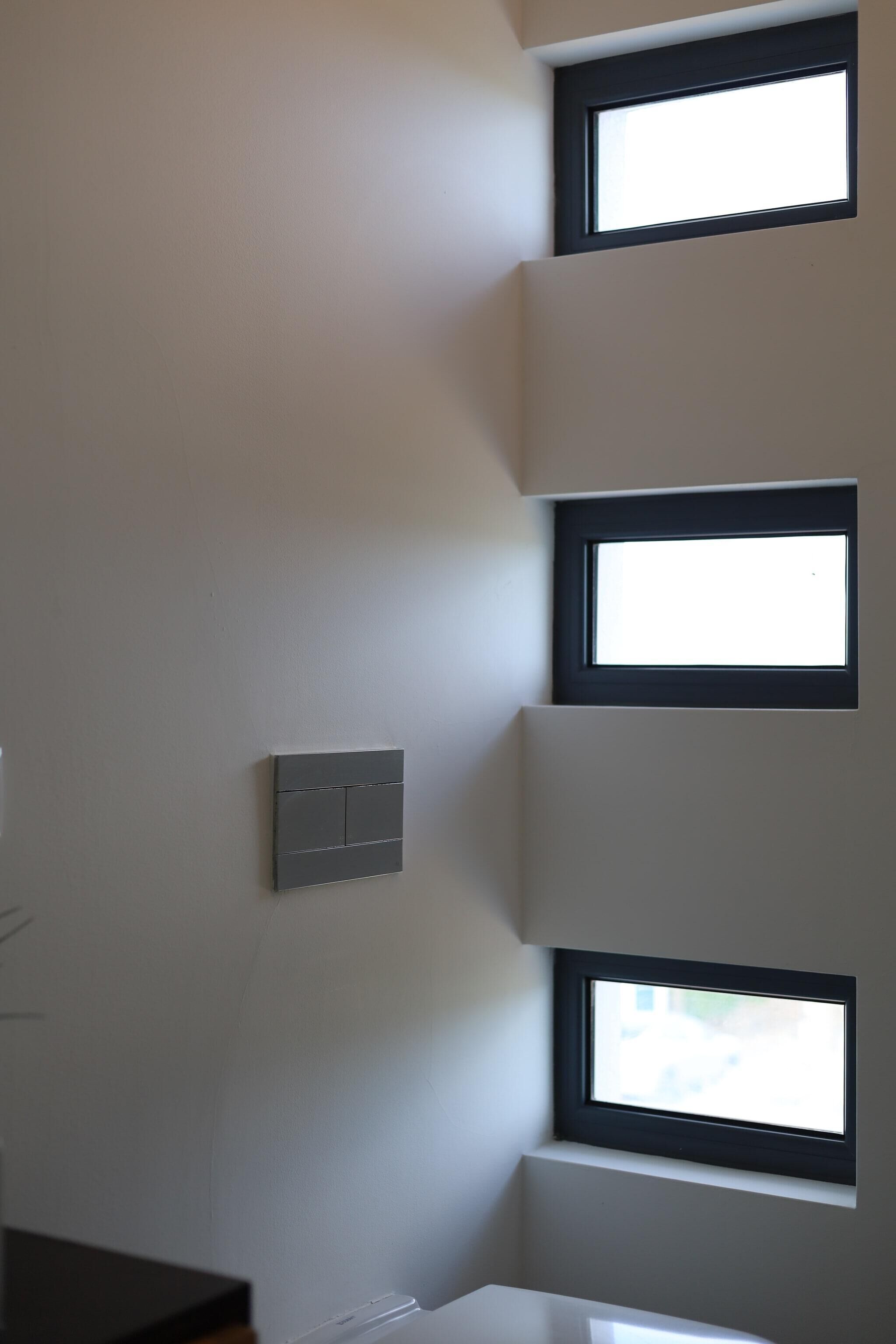 Pareda com vários janelões retangulares e um interruptor de luz.