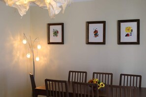 Un'area pranzo con tavolo, sedie e tre opere d'arte appese alla parete.