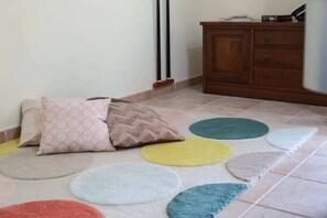 Una stanza con un tappeto decorato, un armadietto in legno e un termosifone a parete.
