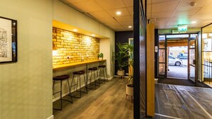 A bar area with a brick wall, wooden floor, and bar stools. - Student Only Buchanan View (Glasgow)