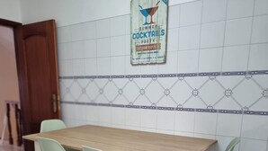 Uma área de refeições com uma mesa de madeira e quatro cadeiras verdes.
